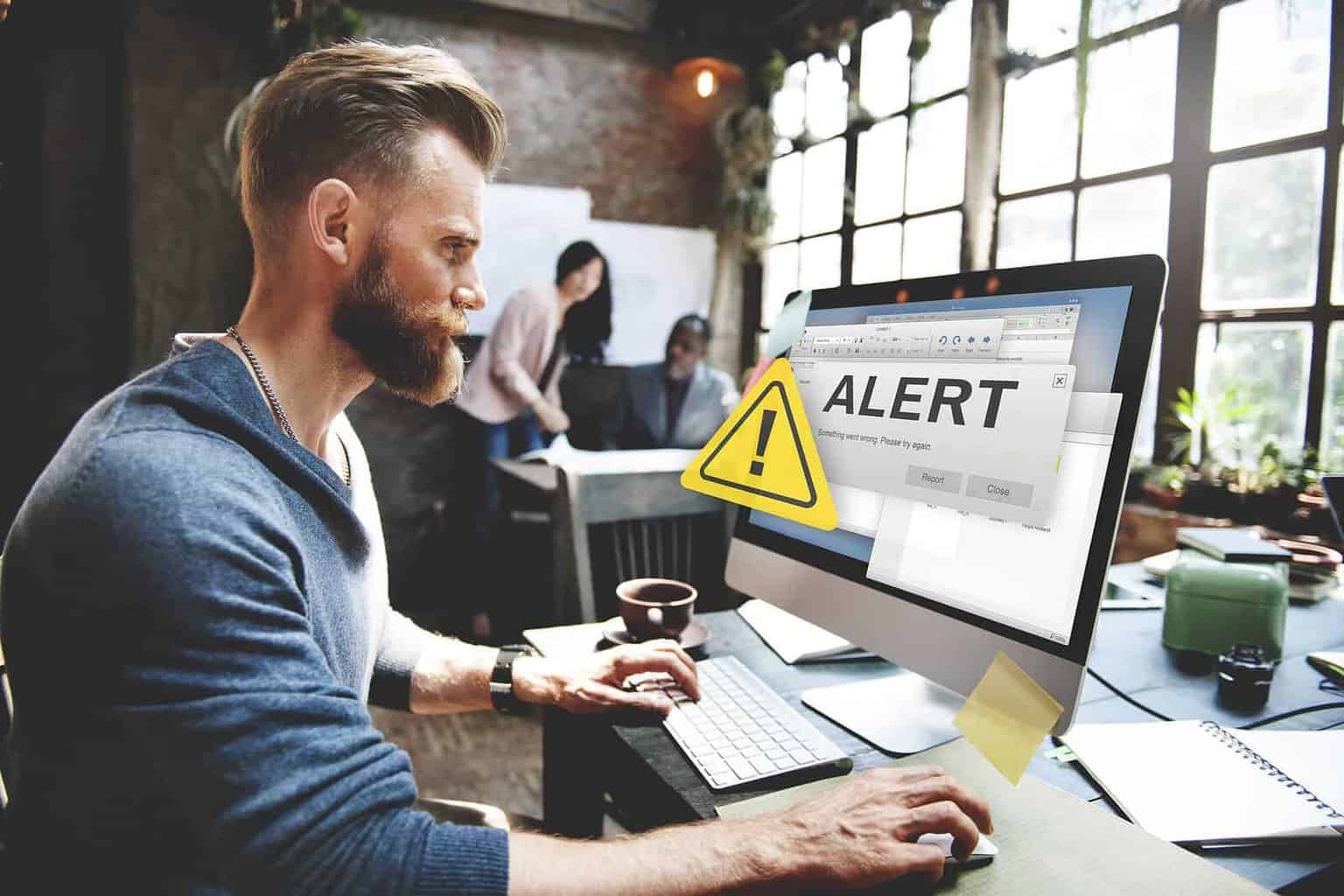 Man with beard looking at computer screen with alert on screen