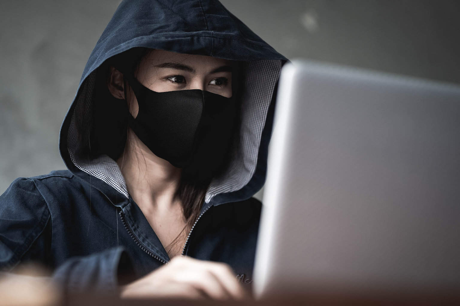 person wearing a face mask sat in front of a laptop